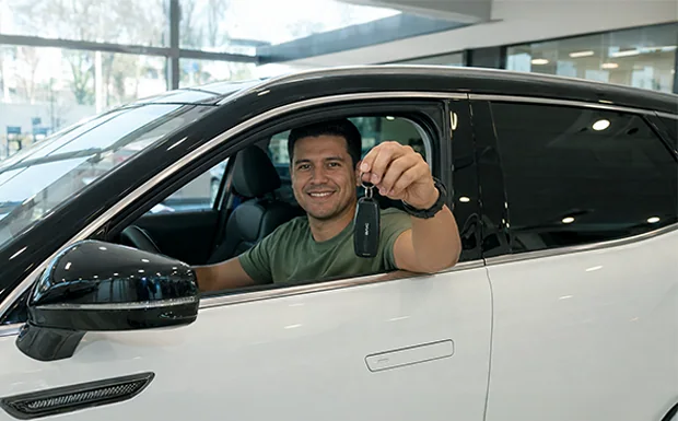 Cliente al volante de su BAIC nuevo mostrando la llave en la entrega