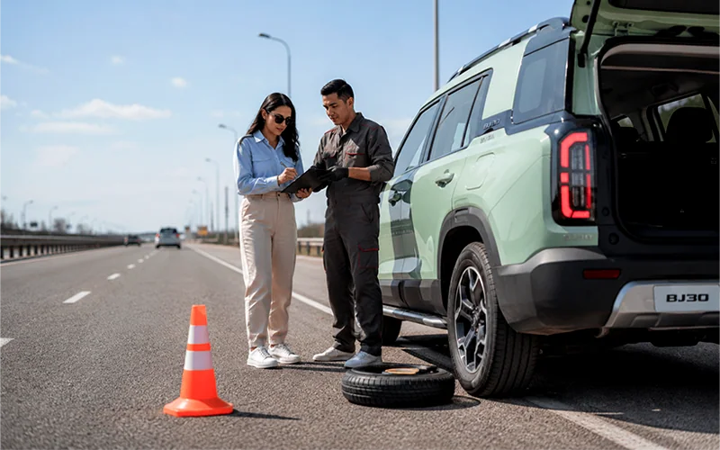 Técnico atendiendo a una pareja al borde de la carretera junto a un BAIC BJ30